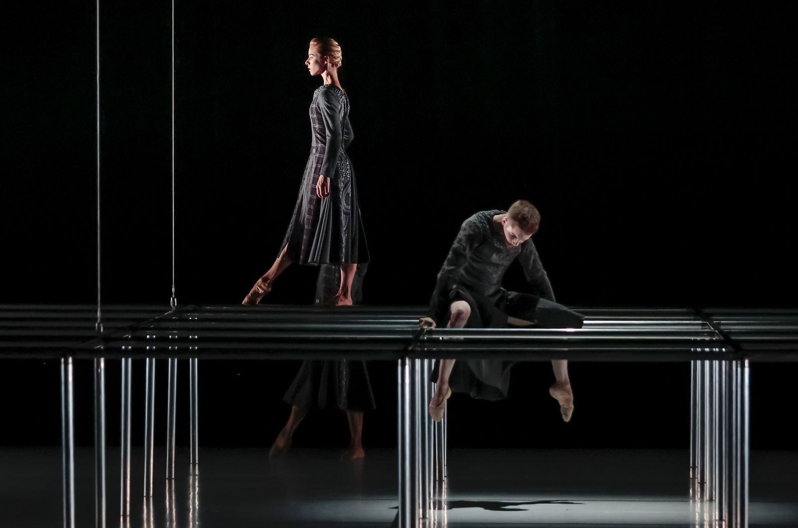 Una estructura metálica limita al principio el movimiento de los bailarines.