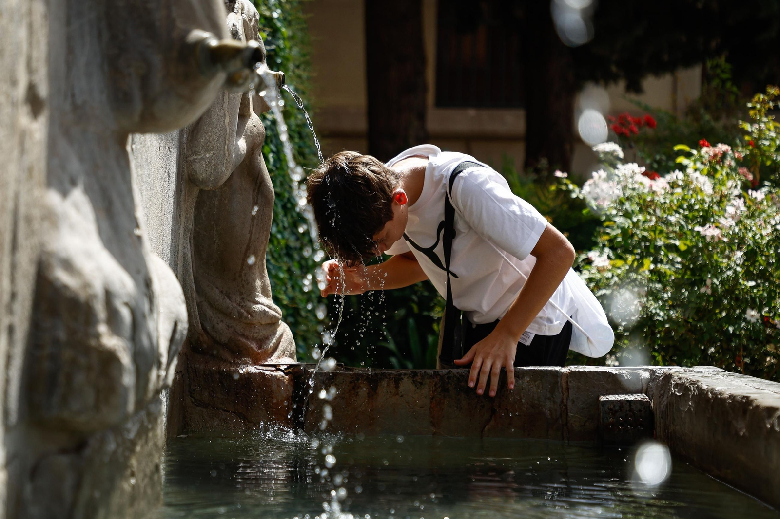 Un joven se refresca en una fuente estos días.
