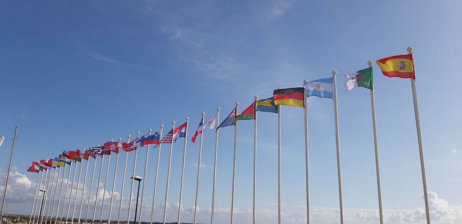 Banderas de los países participantes ondeando al viento junto a la playa asfáltica de Puerto Sherry.