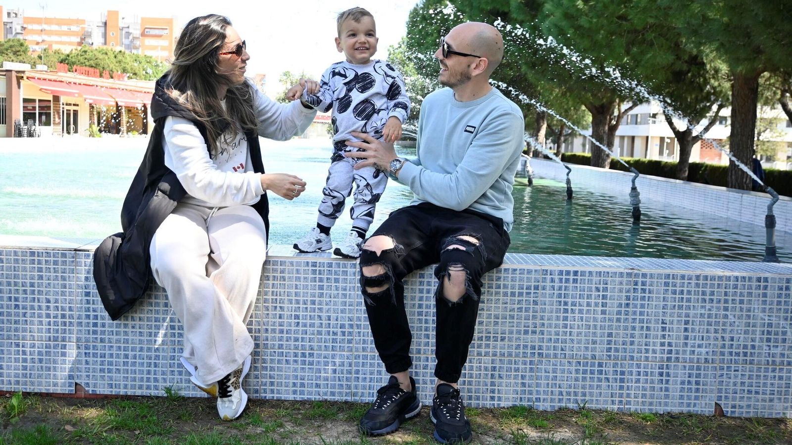Fabio sonríe junto a sus padres en una fuente de la Avenida de Andalucía.