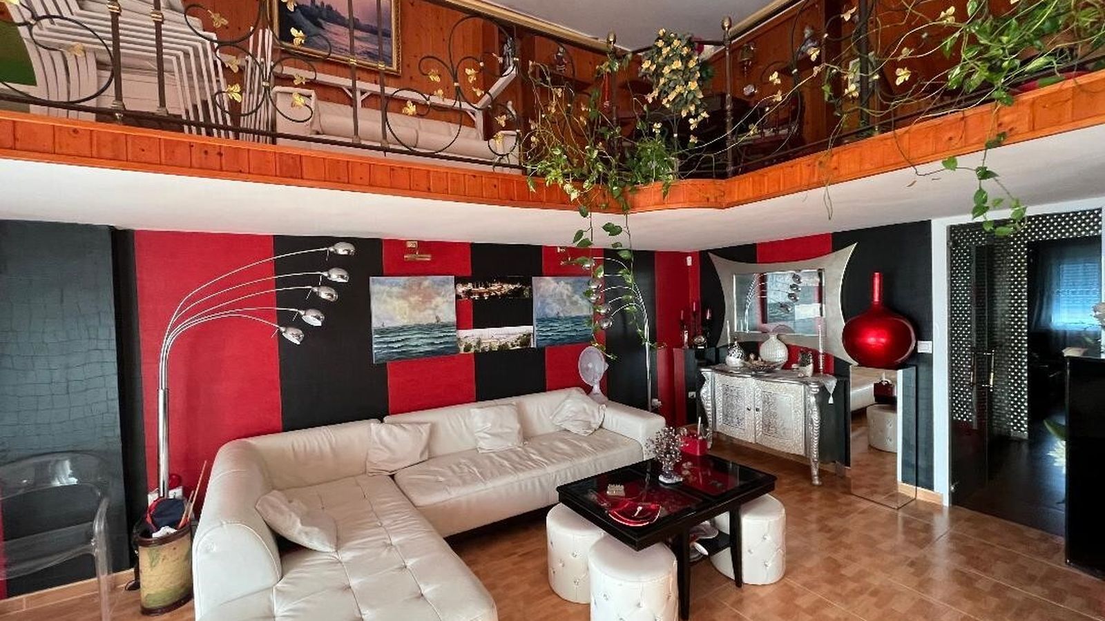 Salón. Combina los colores del sofá de piel blanco con el rojo y negro de sus paredes