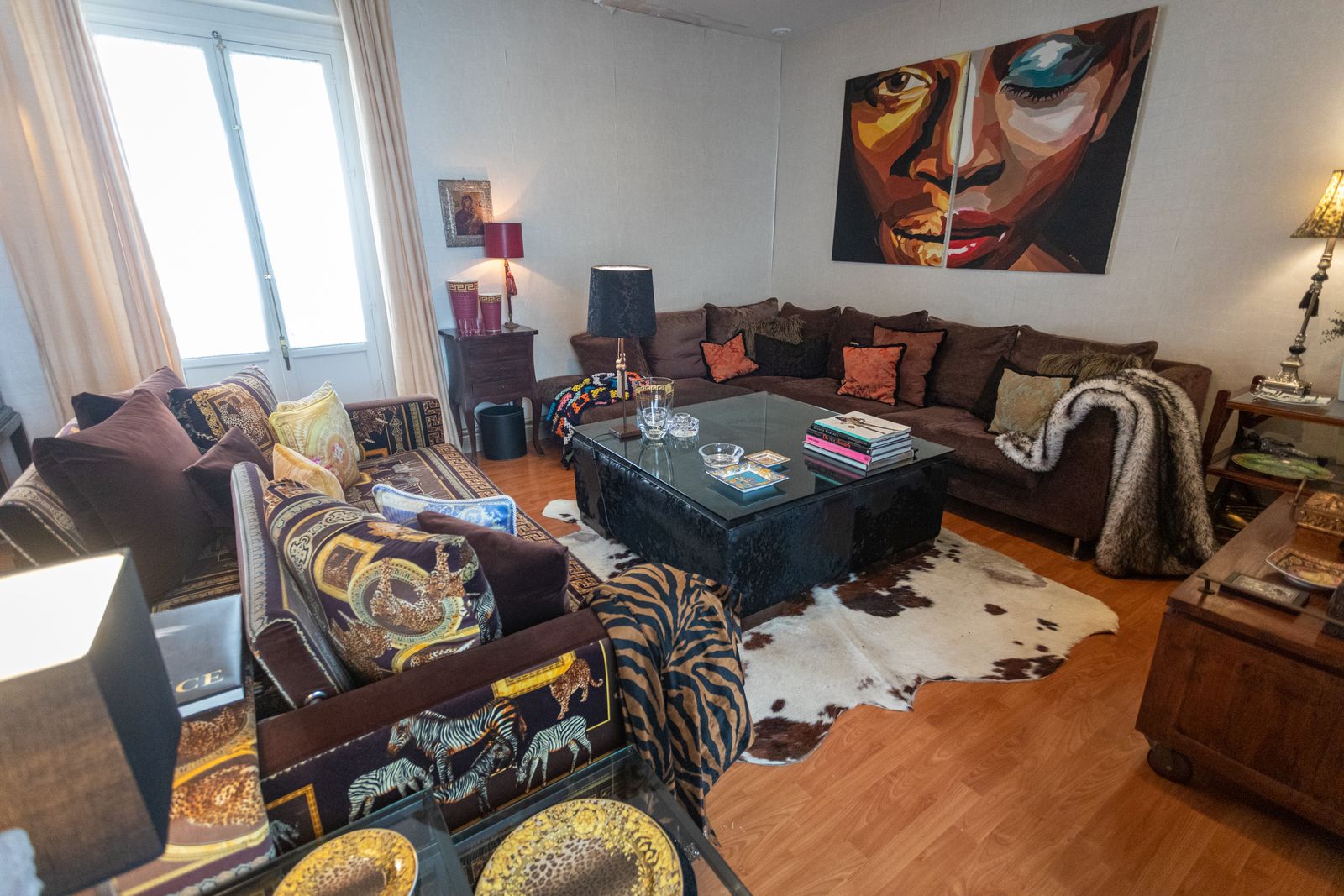 Salón. Mesa baja de piel de toro junto a un sofa tapizado en color berenjena y otro de estampado en Savanna. La alfombra es de piel de vaca.