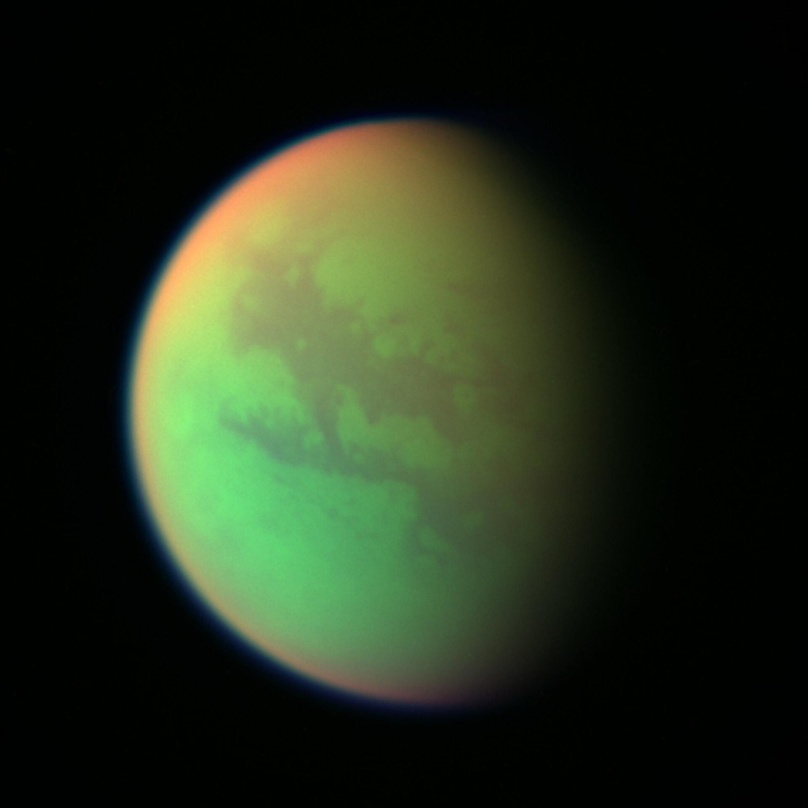 Composición en falso color creada con imágenes tomadas durante el sobrevuelo más cercano de la nave espacial NASA/ESA/ASI Cassini a Titán en 2025. El verde representa las zonas en las que Cassini puede ver la superficie. El rojo representa las zonas altas de la estratosfera de Titán. El azul a lo largo del borde exterior de la luna representa las longitudes de onda del violeta visible en las que se ven mejor la atmósfera superior y las brumas desprendidas.
