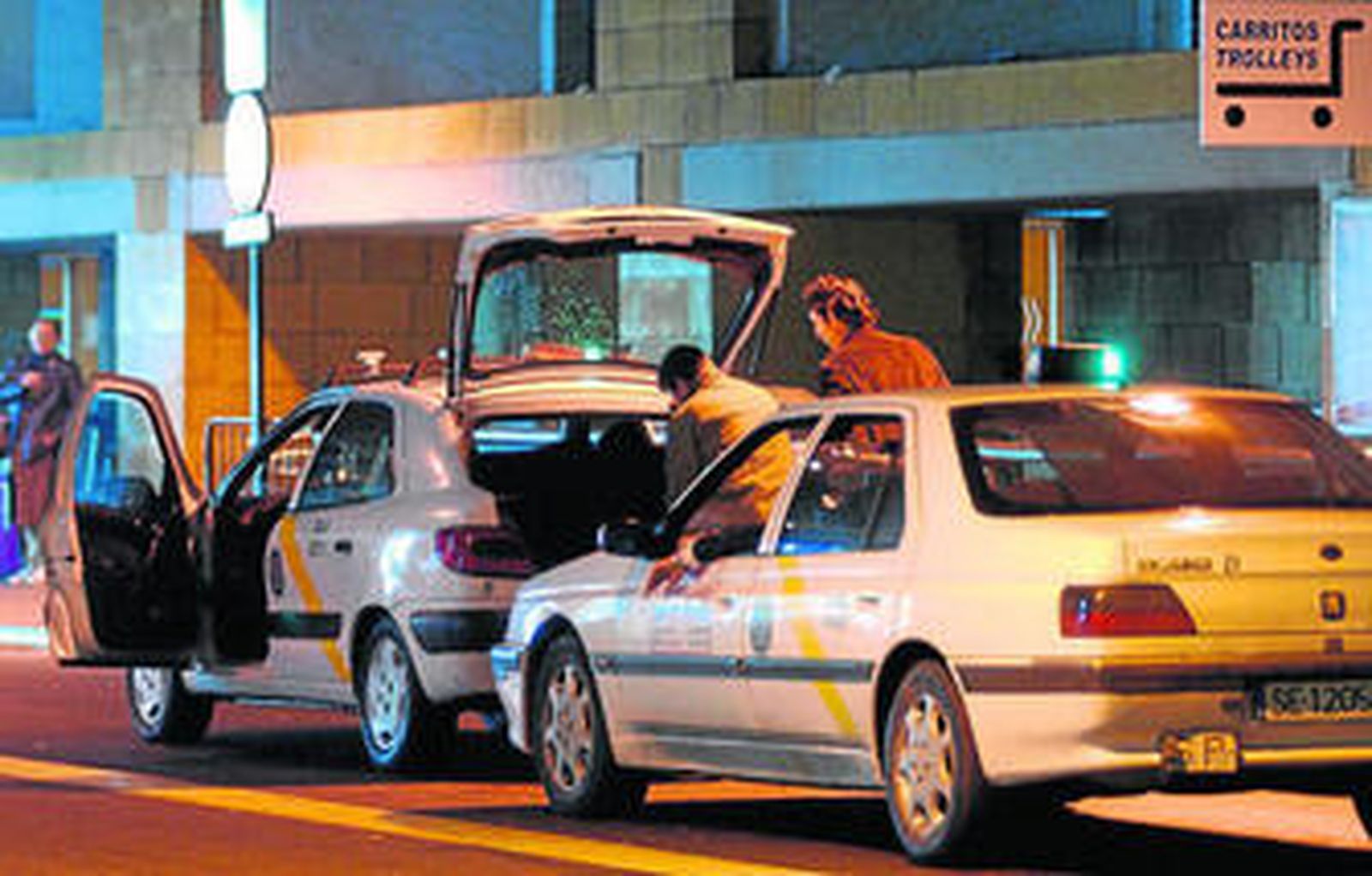 Un taxista ayuda a sacar las maletas a un usuario al llegar al aeropuerto de Sevilla.