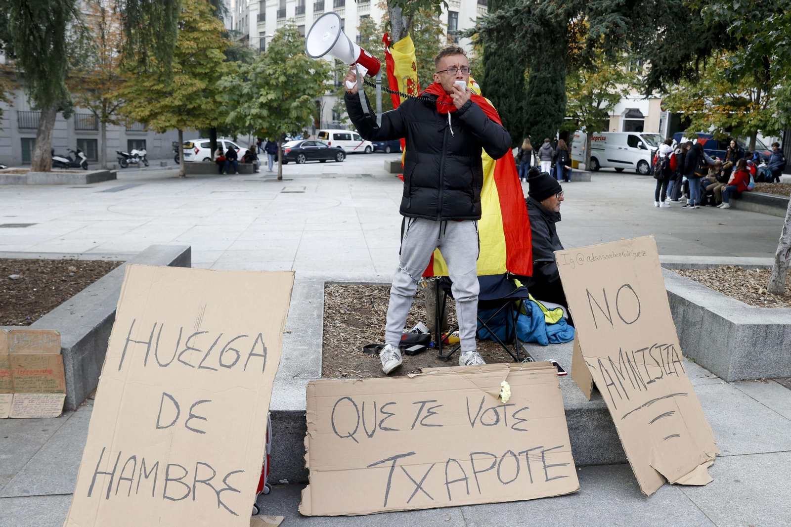 Un joven se encadena ataviado con una bandera de España frente al Congreso contra la amnistía