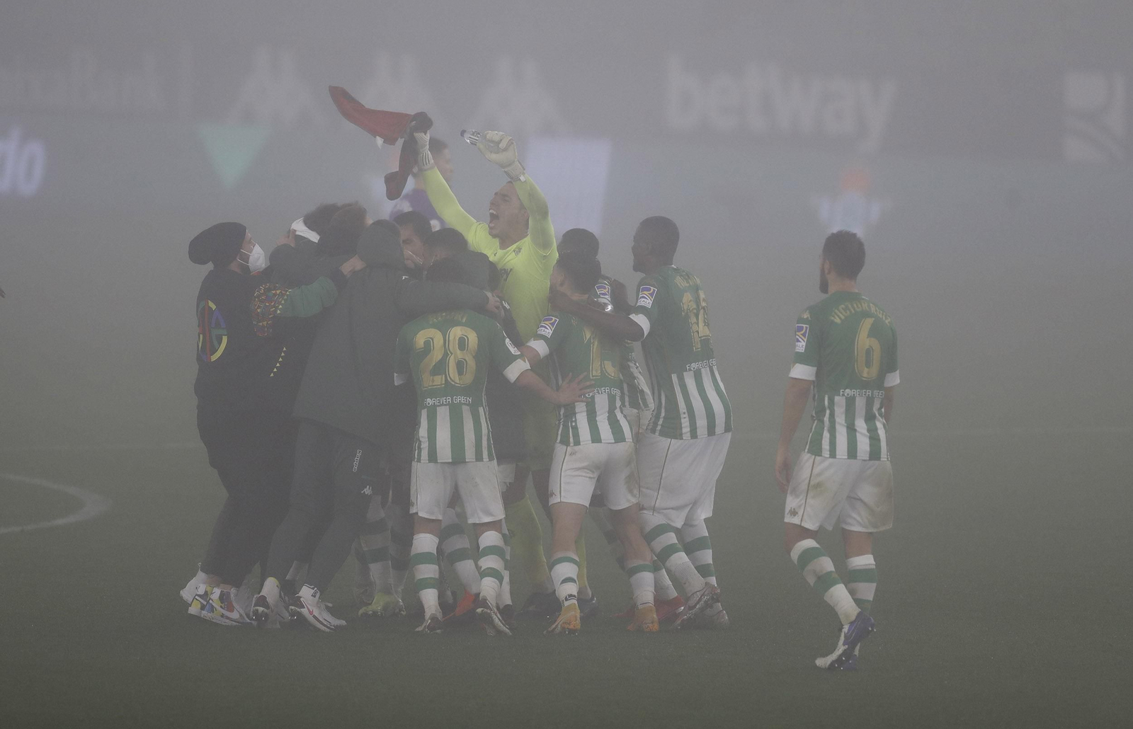 Los futbolistas del Betis celebran el triunfo eufóricos entre la niebla.