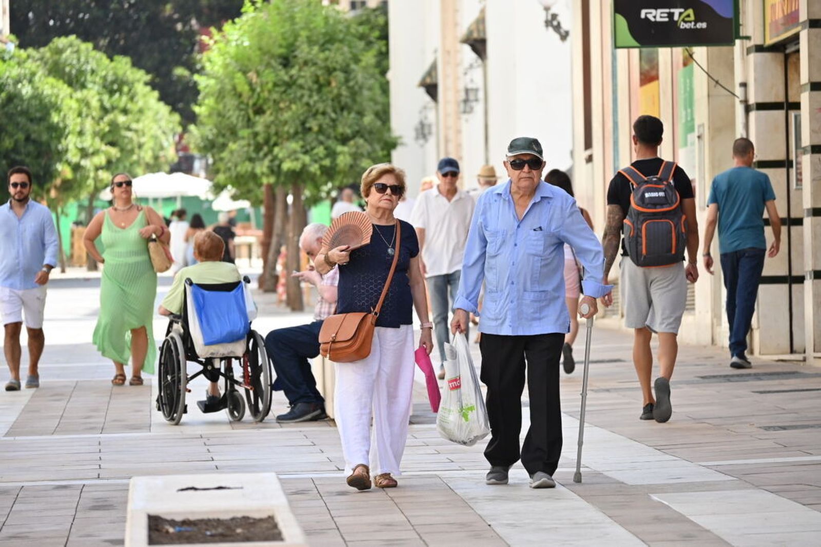 Varias personas combaten el calor en huelva con abanicos y sombra