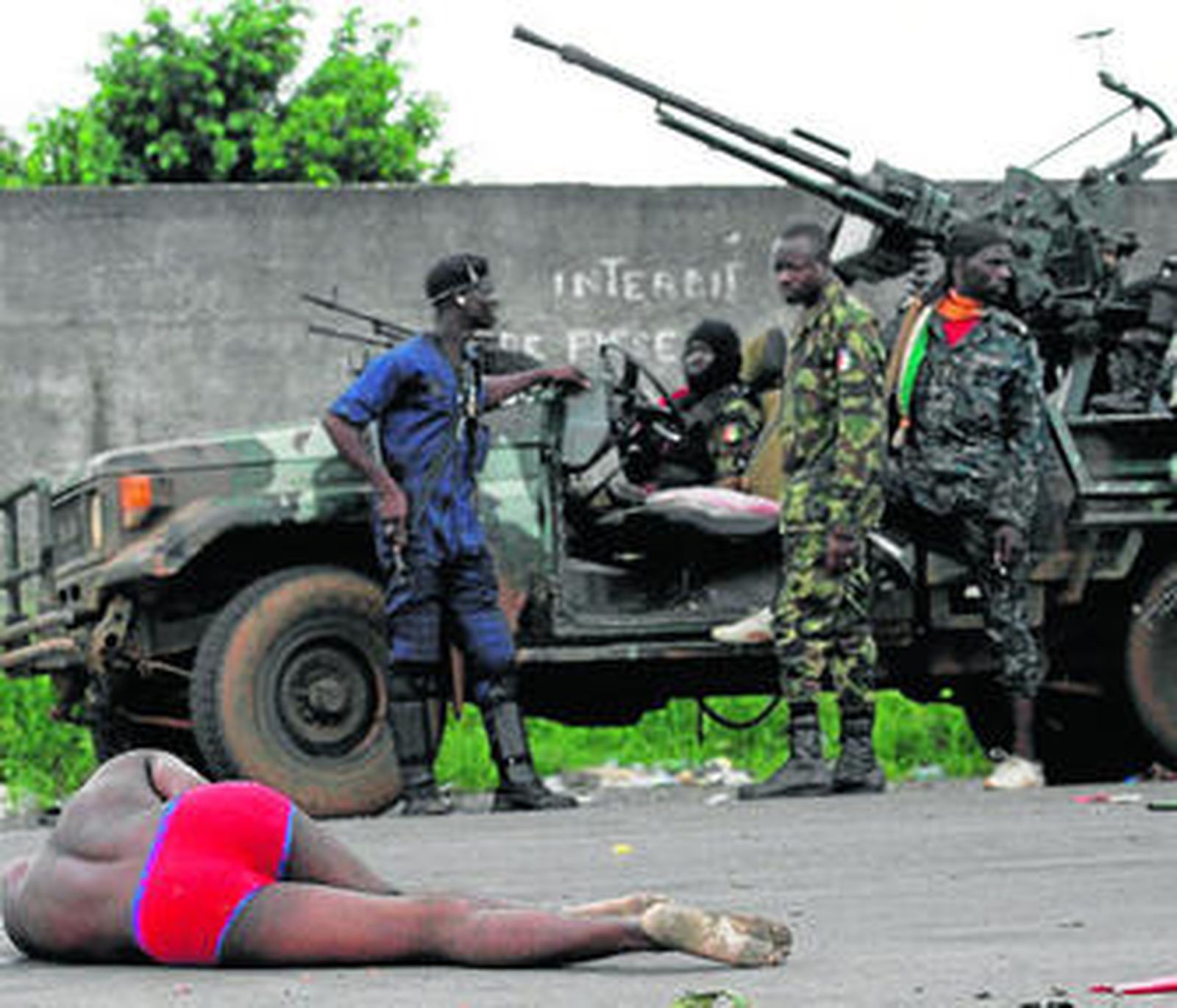 Soldados de Ouattarra observan el cadáver de un rival en las inmediaciones de Abiyán.