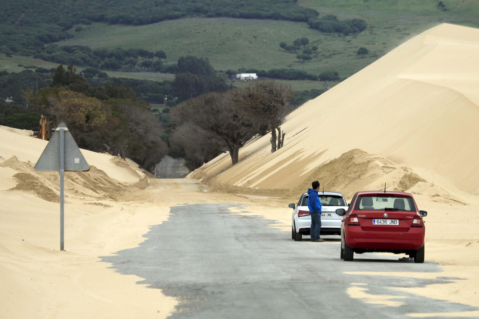 Dos coches parados en la A-2325, invadida por la arena de la duna.