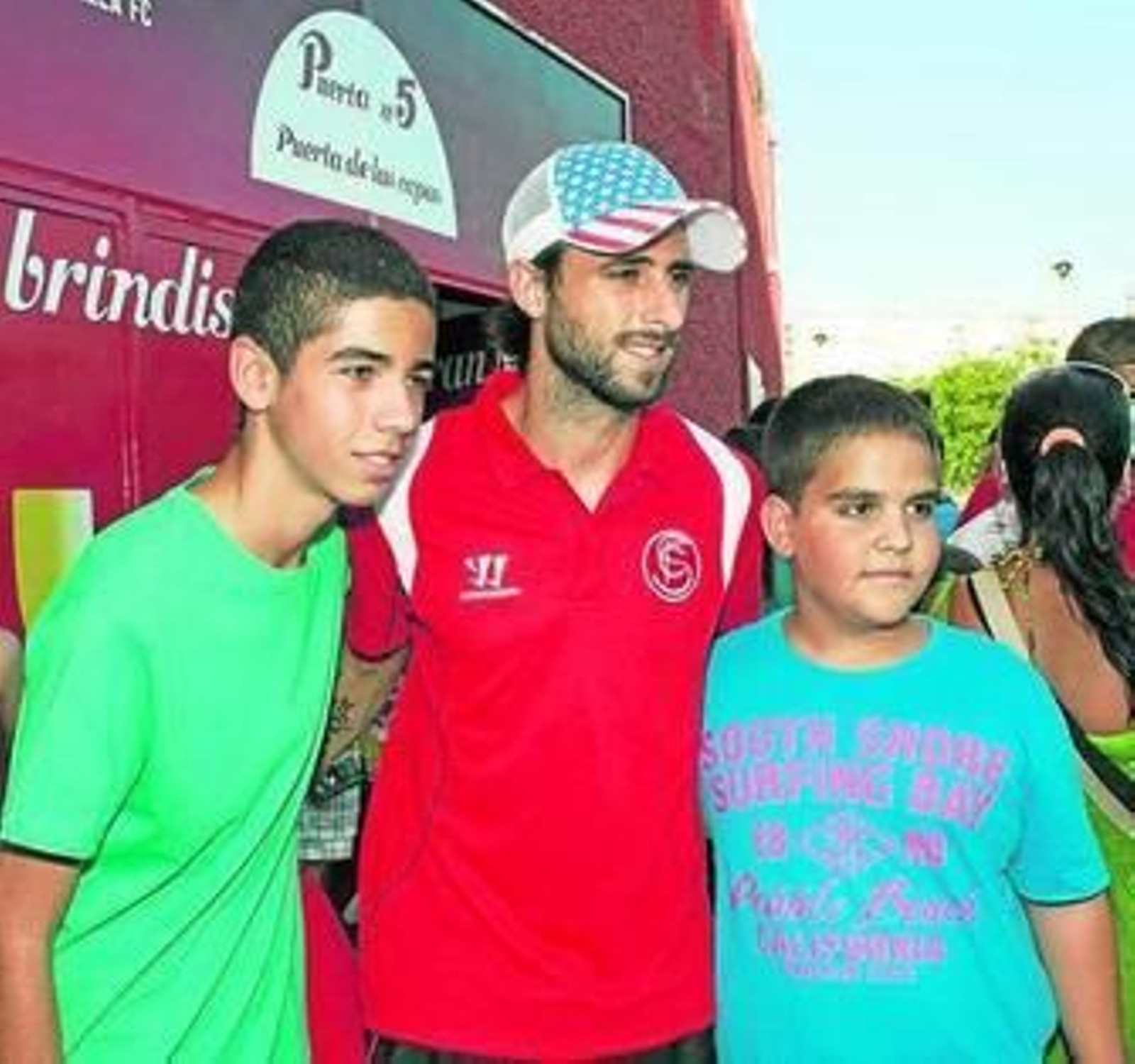 Pareja posa con dos jóvenes aficionados junto al bus del Sevilla.