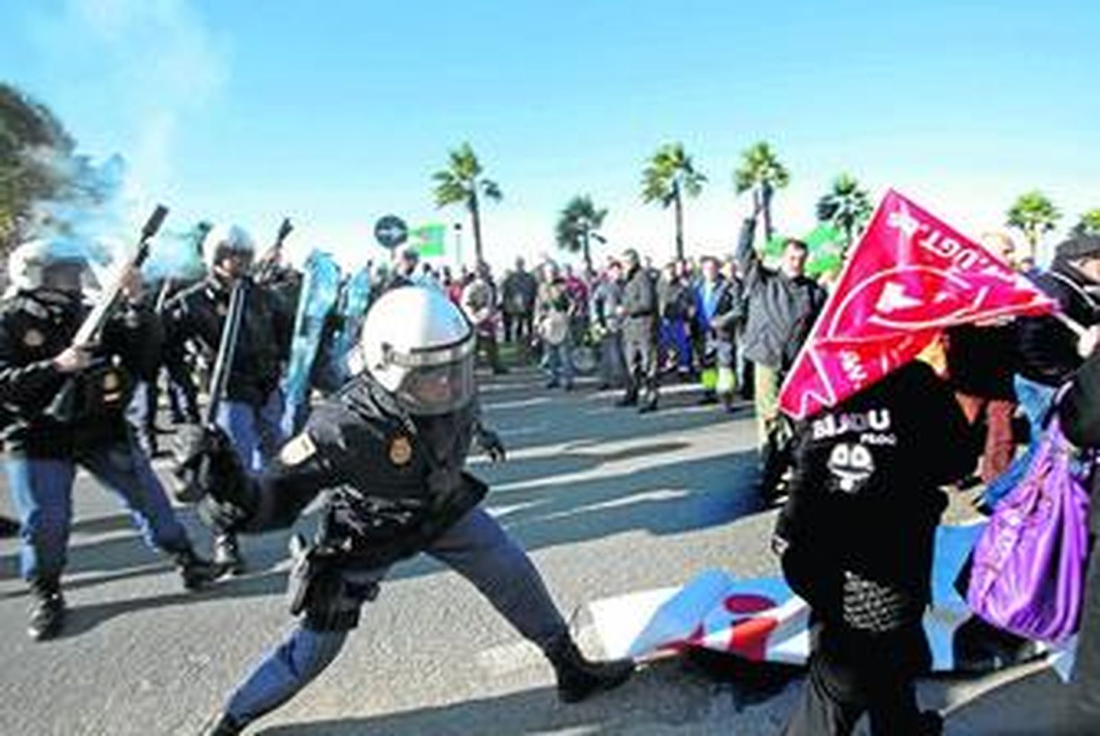 Un agente antidistubios carga contra los manifestantes, ayer en La Línea.