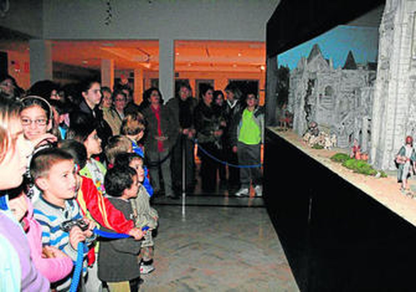 Numerosos niños observan el portal de belén instalado en el hall del Centro Cultural de la Villa.