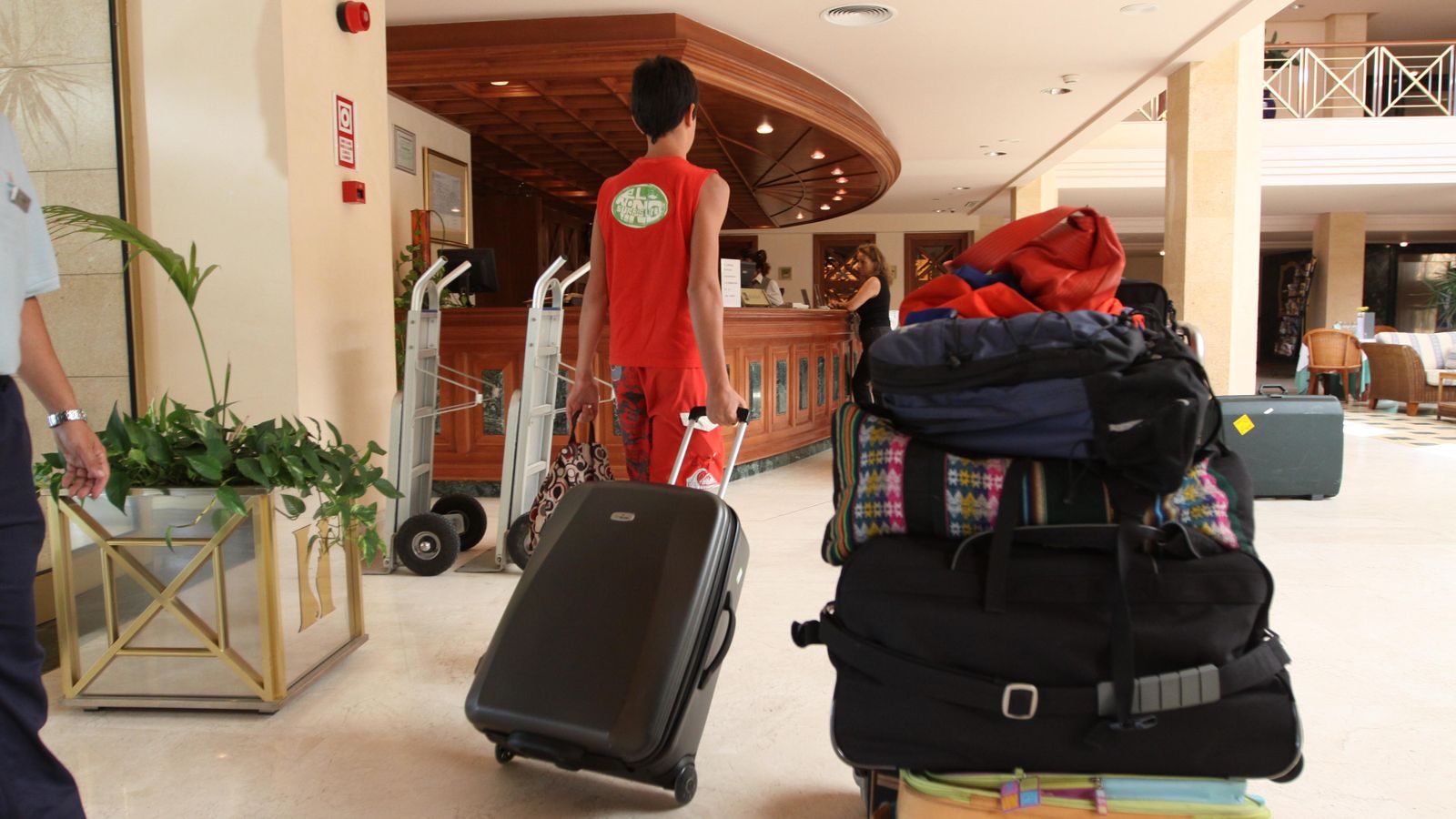 Un joven lleva una maleta en el interior de un hotel.