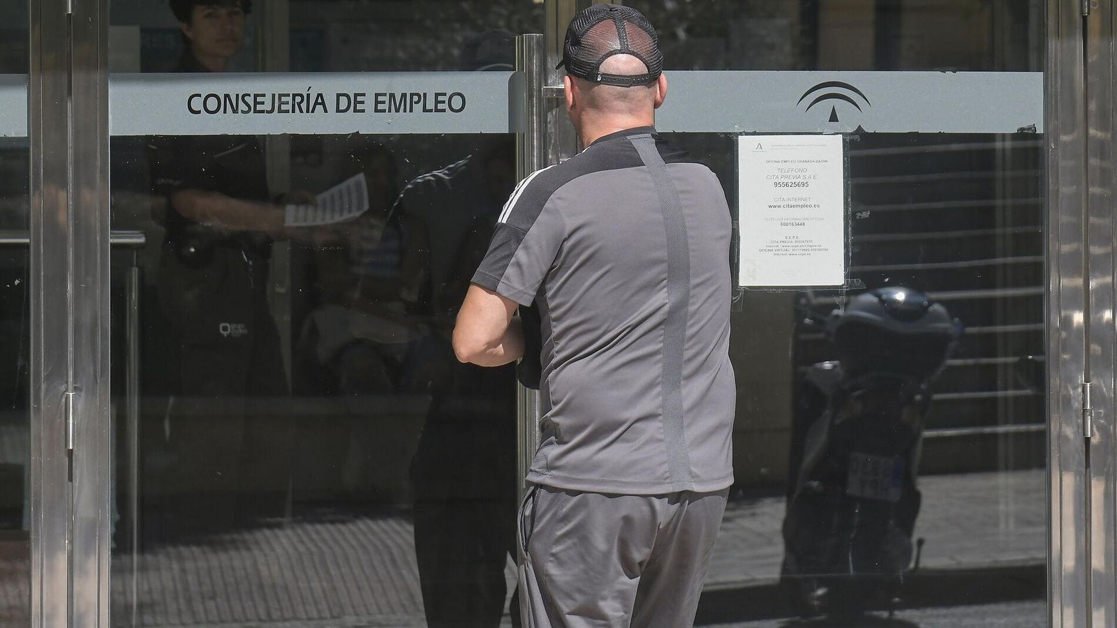 Un hombre accede a la sede de la Consejería de Empleo, en la que un cartel avisa de la necesidad de cita previa