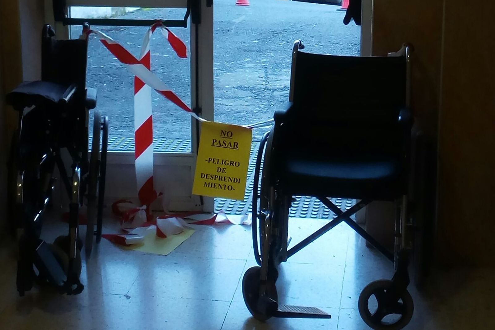 Cartel precariamente instalado entre dos sillas avisando del riesgo de desprendimientos.