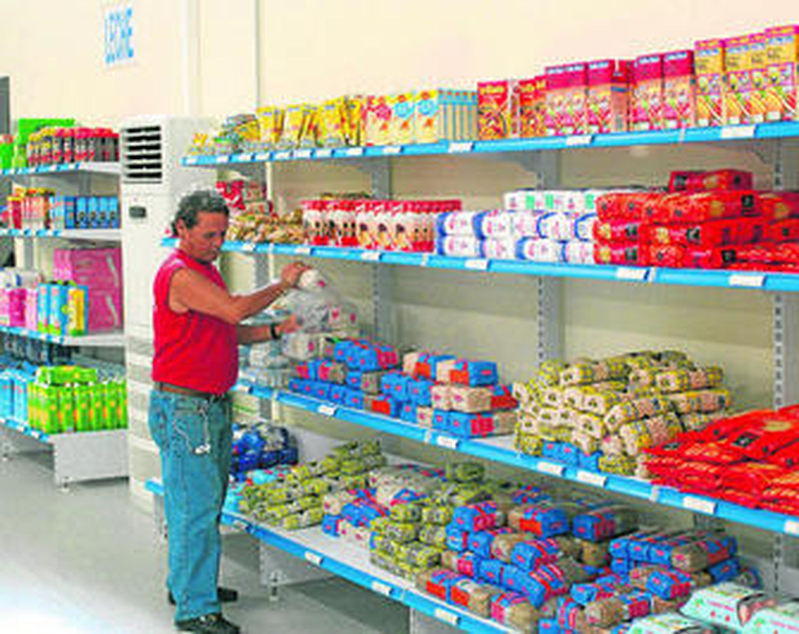 Un empleado repone artículos en el economato de la calle Narciso Bonaplata.