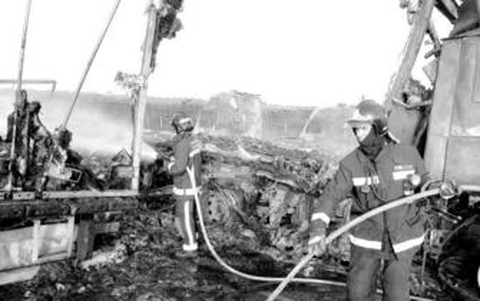 Los bomberos sofocan las llamas de los nueve camiones calcinados.