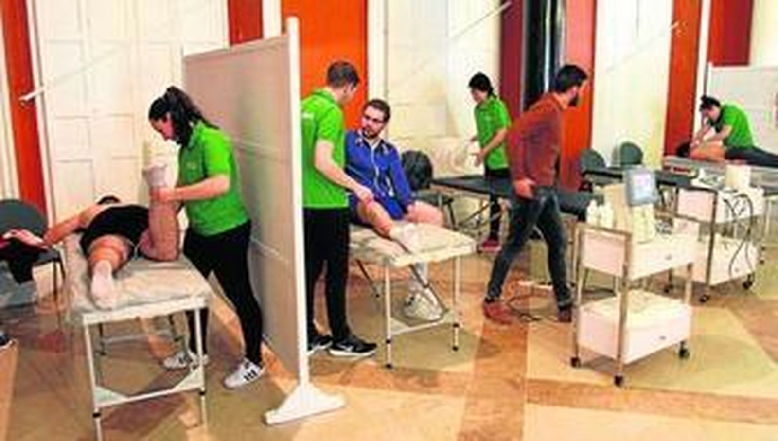 Fisioterapeutas tratando ayer a costaleros en el centro habilitado en el Salón de Chimeneas de la Casa Colón.