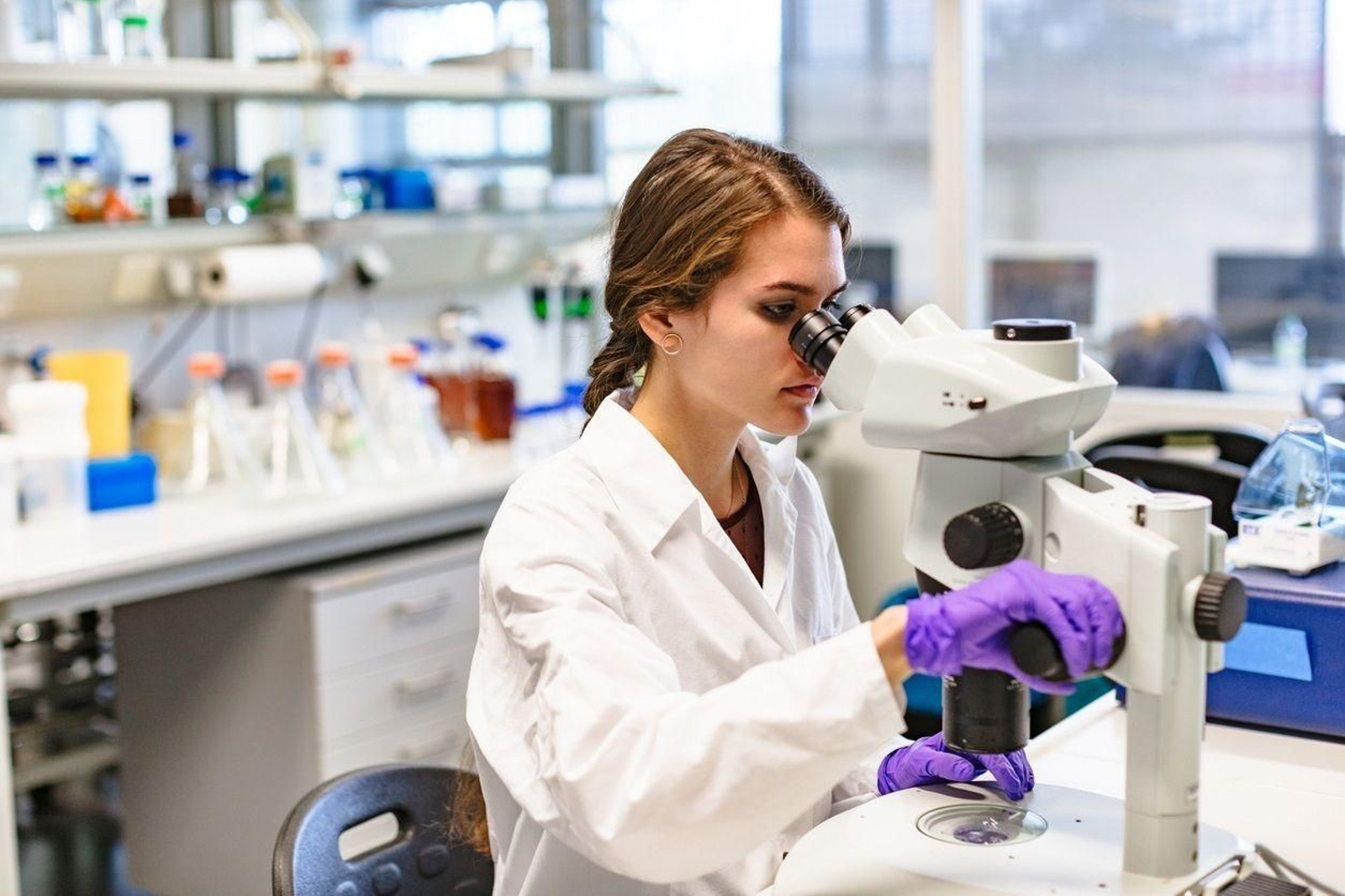 Una científica observa a través de un microscopio. Una científica observa a través de un microscopio.