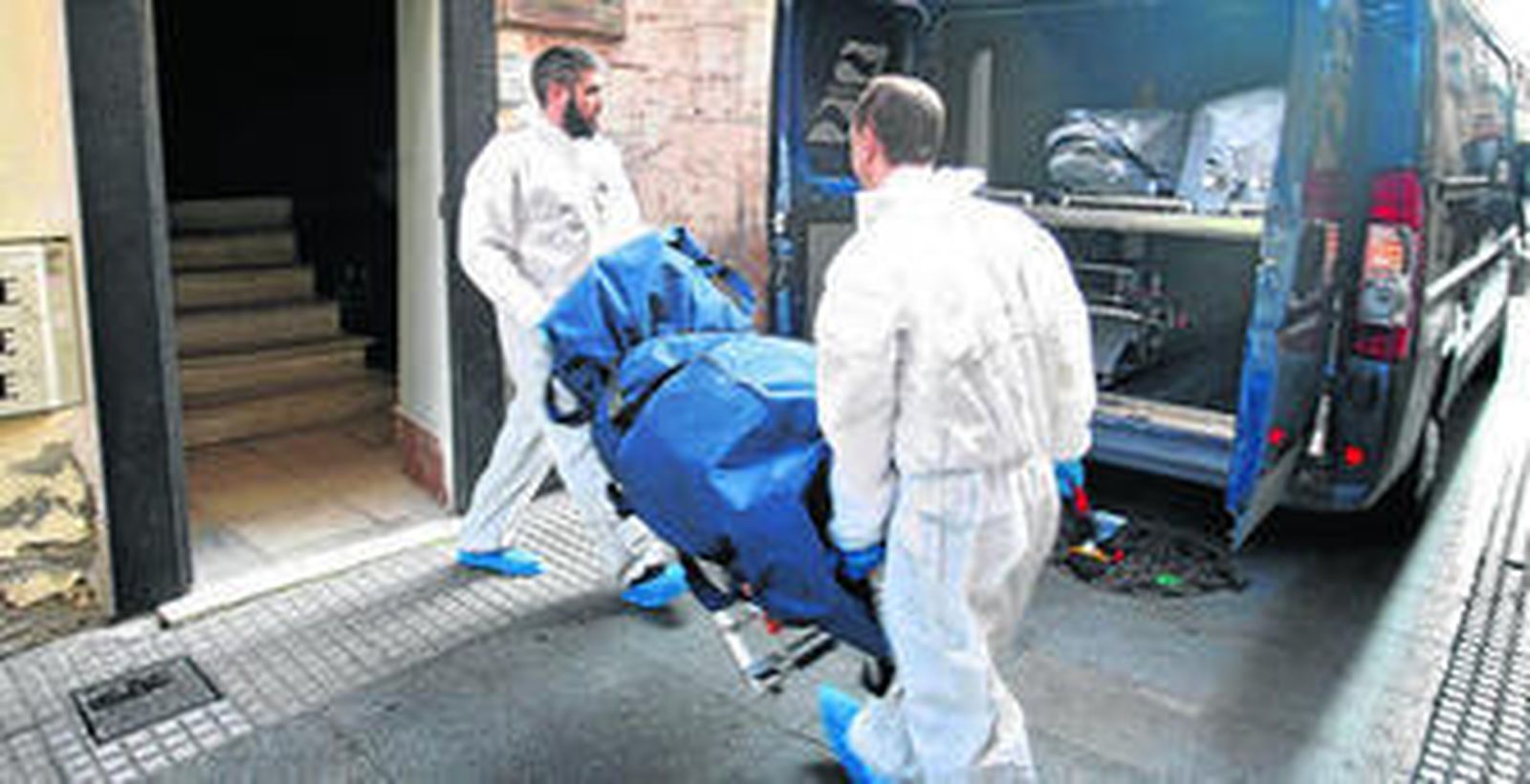 Trabajadores de los servicios funerarios retiran los restos de la fallecida del piso donde fue encontrada.