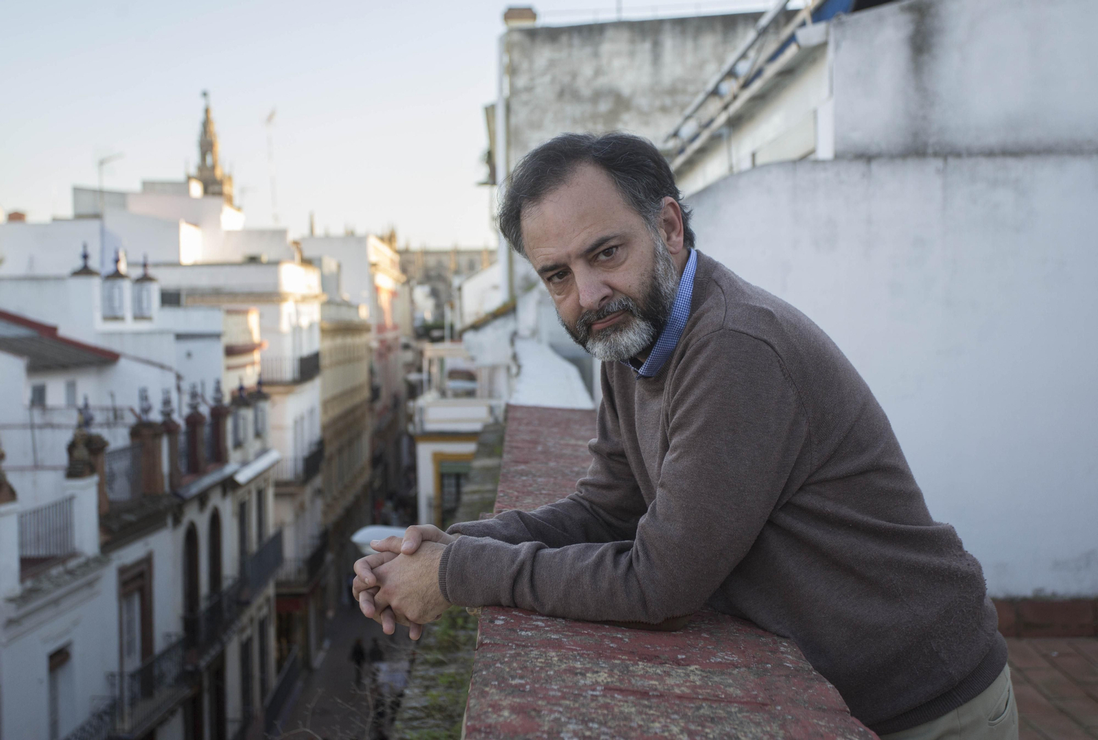 José Fernando Gabardón de la Banda, asomado a una terraza de la calle Sierpes, con la Giralda al fondo.