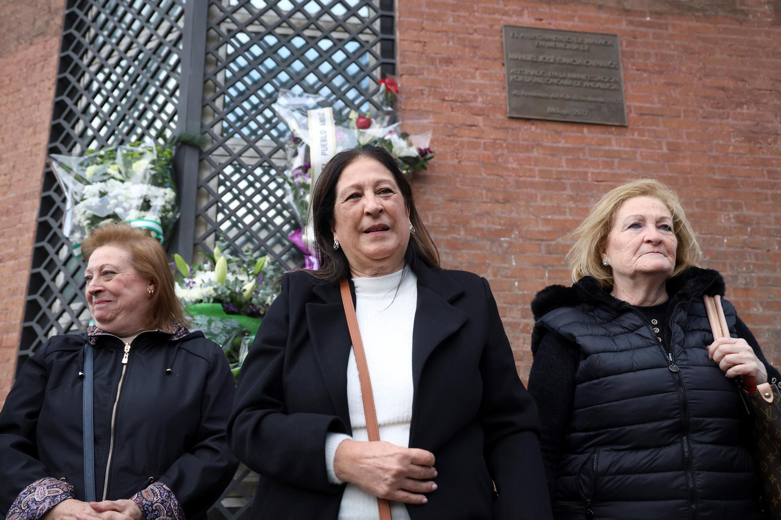 Las hermanas de Manuel José García Caparrós ponen flores delante de la placa donde lo asesinaron