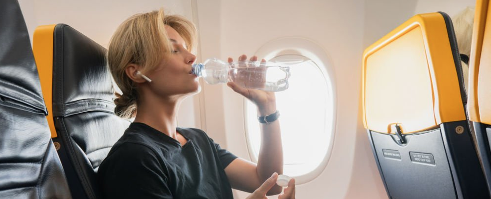 Mujer bebe de una botella de agua durante un trayecto en avión