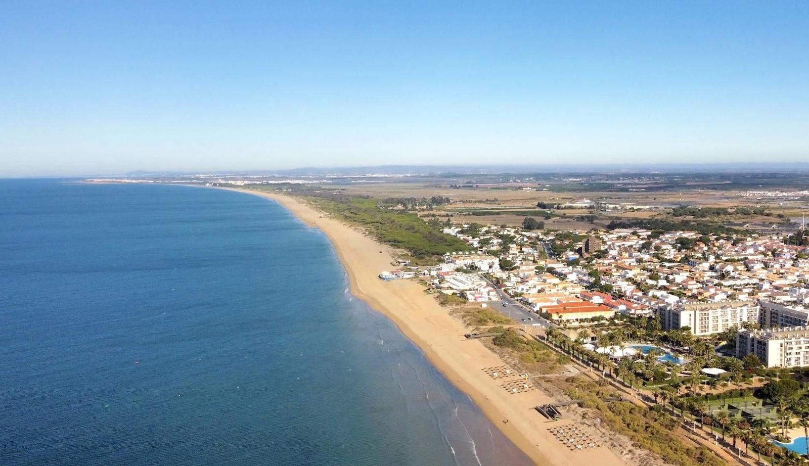 Una playa con pocas edificaciones y mucha naturaleza