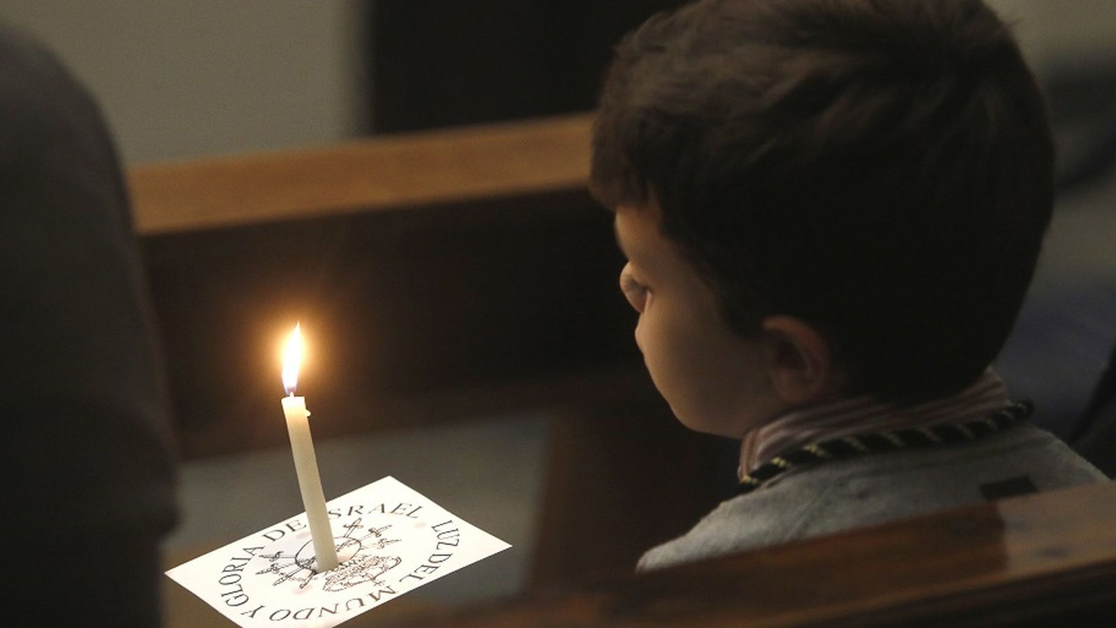 Un niño porta una vela durante la celebración de la Palabra.