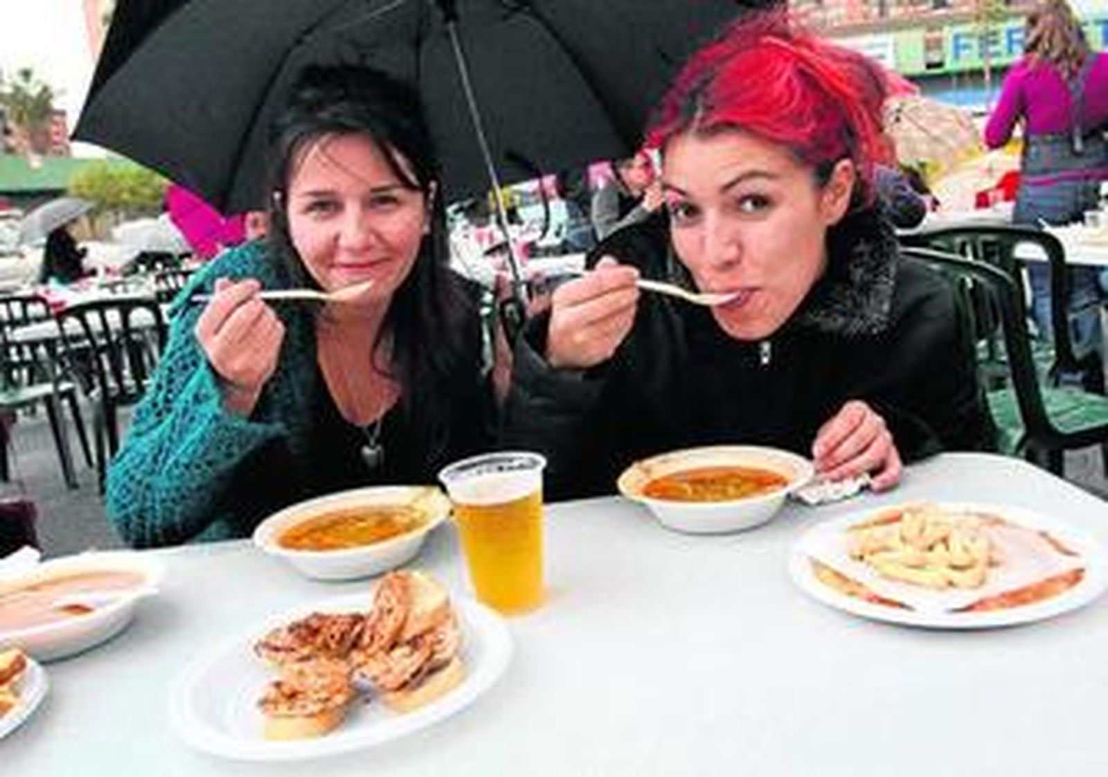 Dos chicas degustan la berza en la Peña Cortijo de Torres, el año pasado.