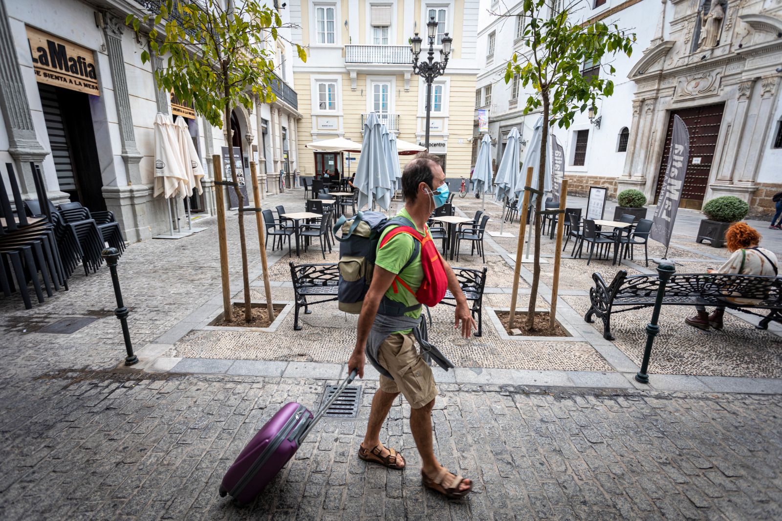 Una persona con mascarilla con una calle de la capital gaditana.