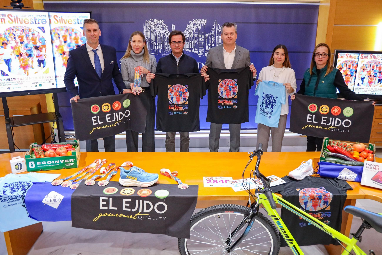 Los representantes institucionales y de la organización muestran las camisetas y material de la prueba.
