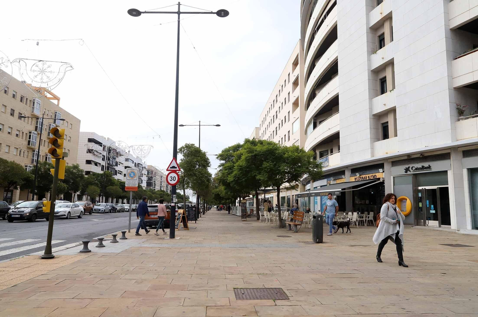 Varias personas pasean esta mañana por la Avenida de la Ría en Huelva.