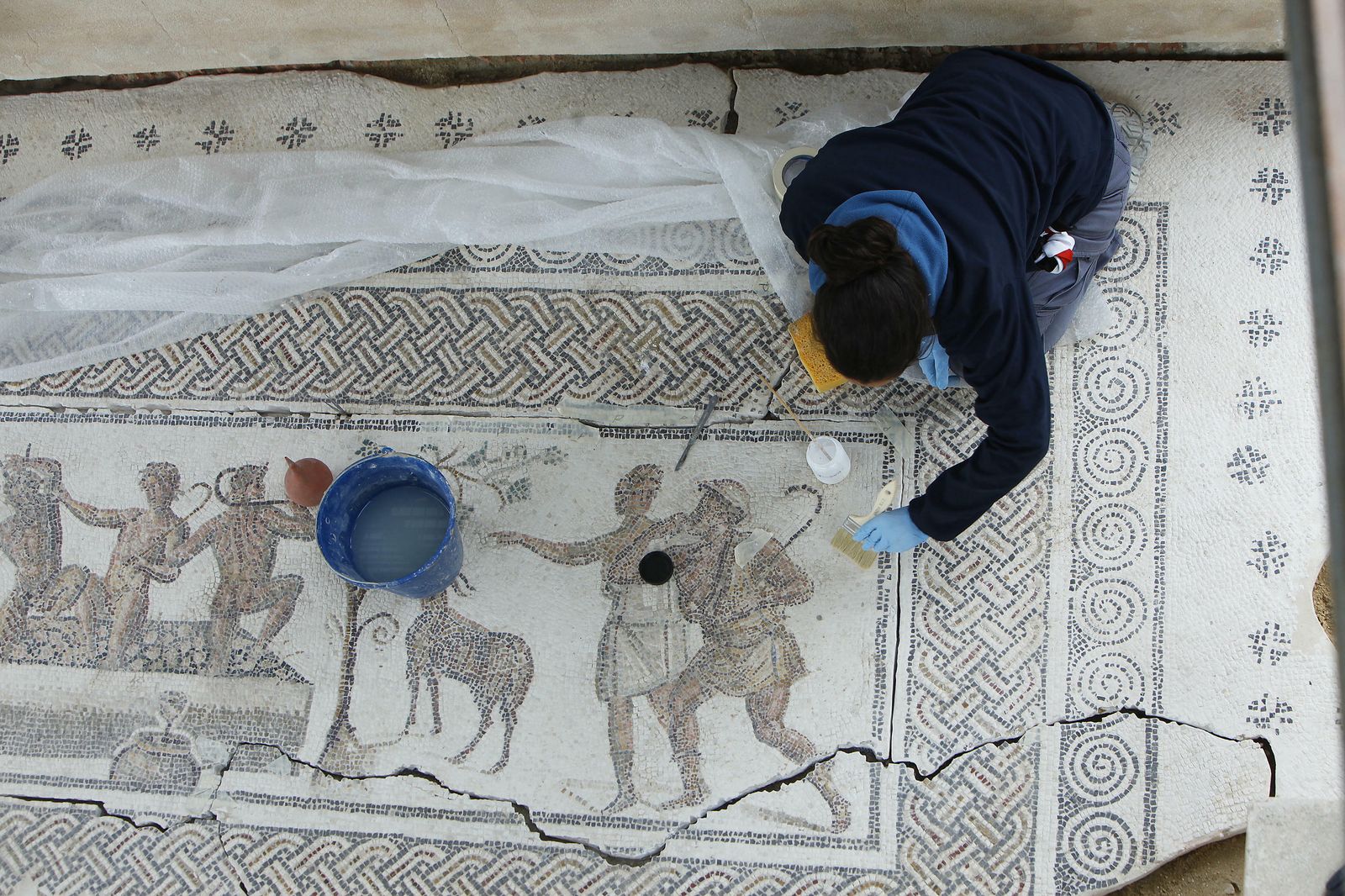 Una trabajadora repone tesela a tesela el mosaico de Los Amores de Zeus en el yacimiento arqueológico del Alcázar, punto más alto de Écija.