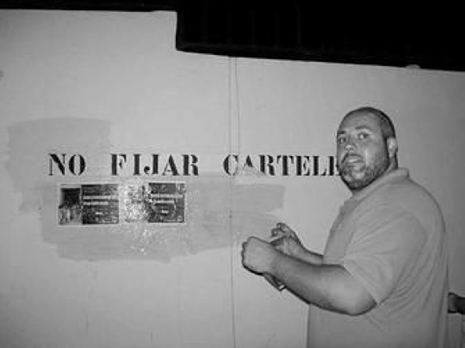 El delegado de AN Málaga, Juan Bermúdez, pega un cartel en el colegio Gamarra.