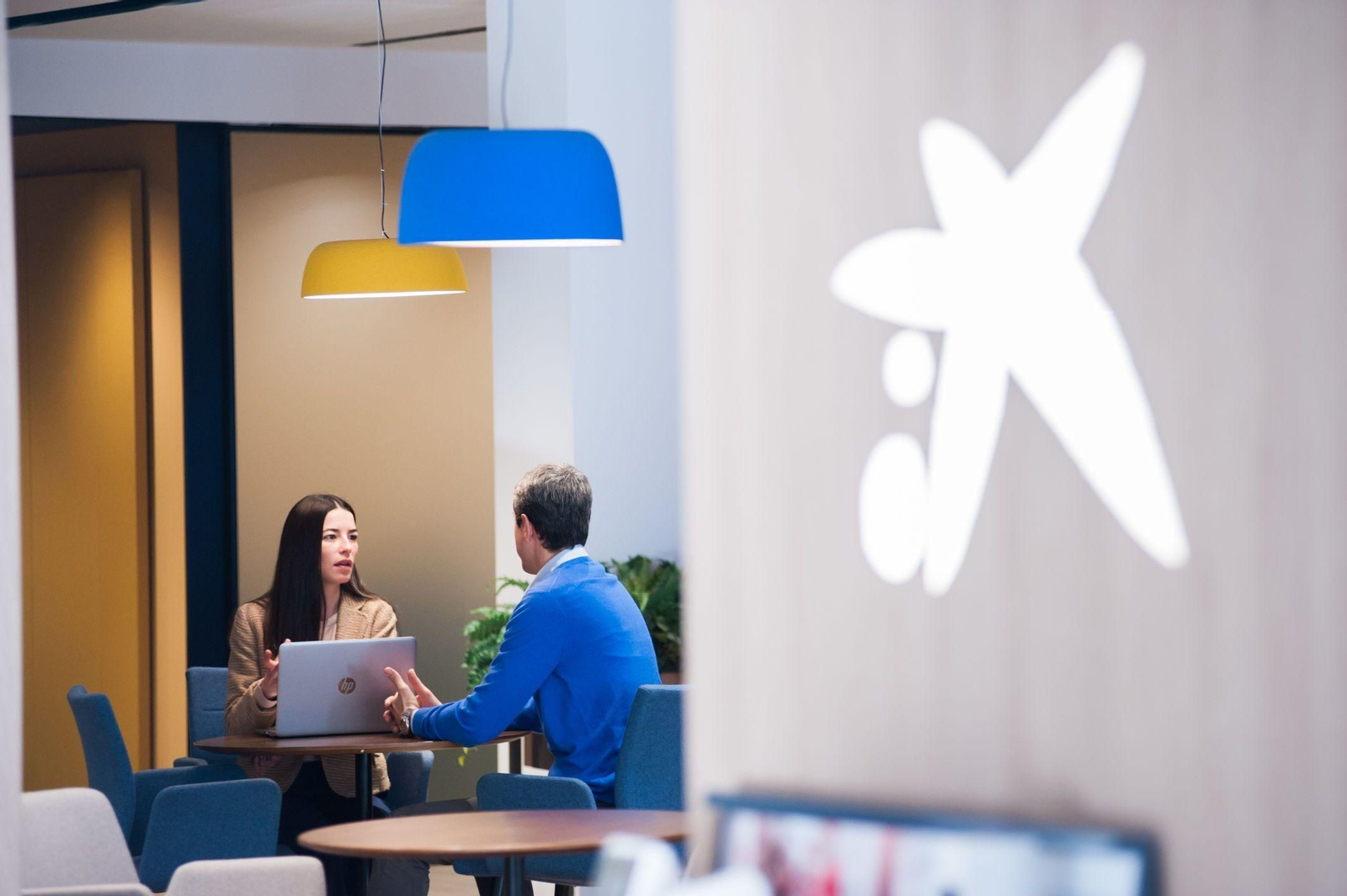 Una empleada de CaixaBank atiende a un cliente en las oficinas de la entidad.