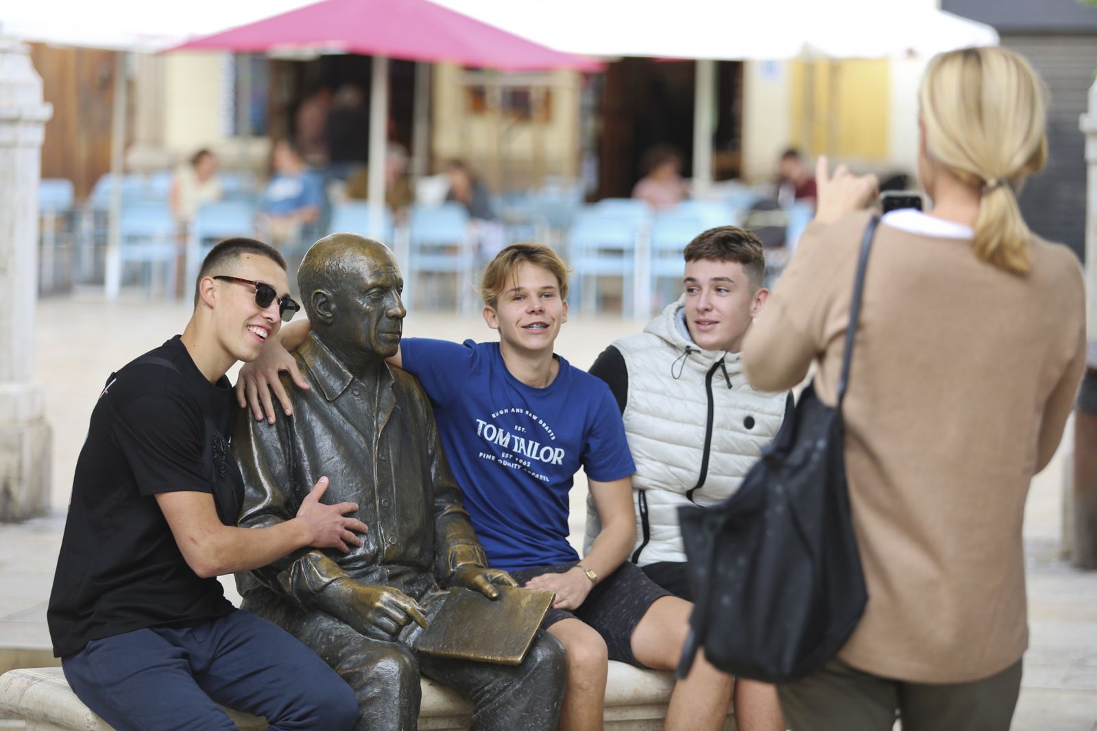 Varias personas se retratan con la estatua de Picasso en la plaza de La Merced.