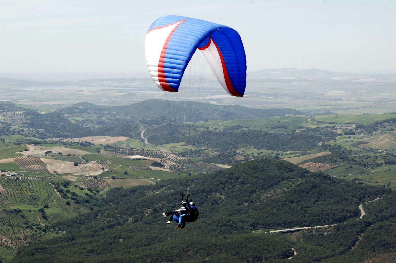 Dos personas practican parapente sobre la sierra