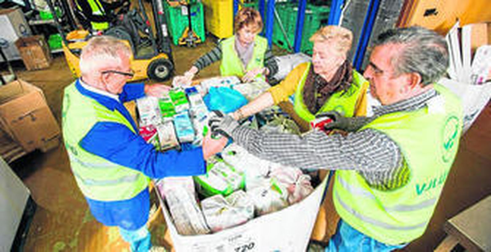 Cuatro voluntarios organizan las cajas de leche recogidas durante la campaña solidaria en Huelva.