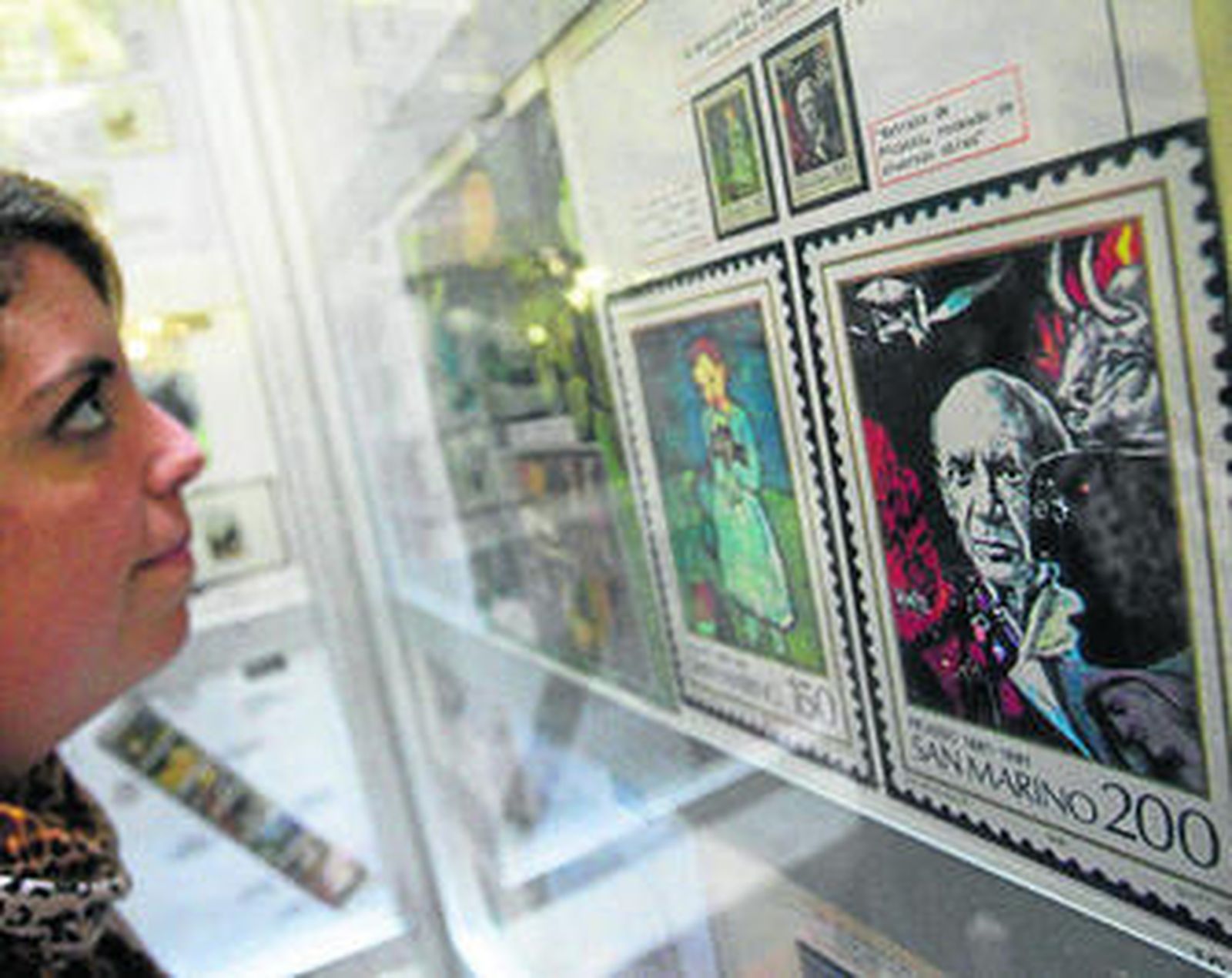 Una visitante observa tras la vitrina los sellos con imágenes de Picasso expuestos en el Archivo Municipal.
