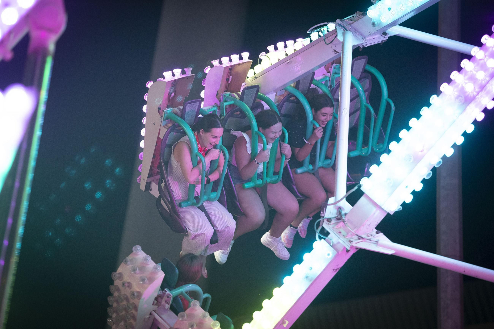 Varias jóvenes disfrutan en uno de los columpios de la Feria del Zaidín