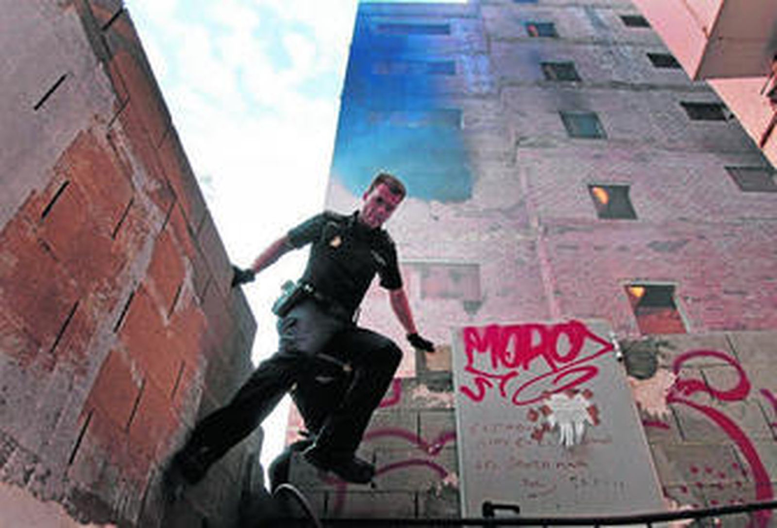 Un agente de la Policía Nacional salta de la valla tras inspeccionar la zona.