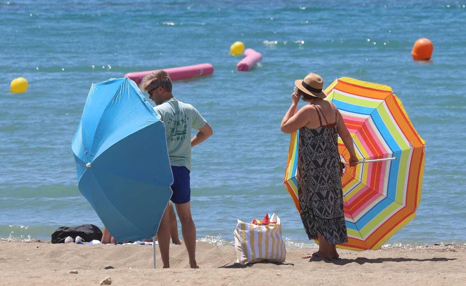 Bañistas colocando las sombrillas en la playa en Málaga, este miércoles.