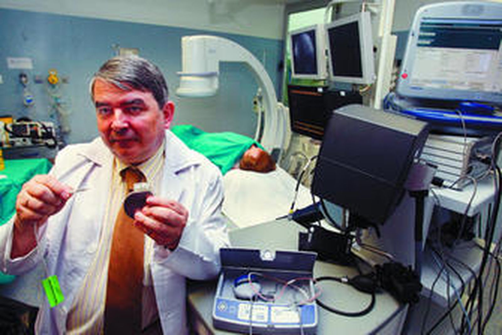 El doctor Javier Alzueta muestra un desfibrilador implantable. Al fondo, una paciente tras ser sometida a un implante.