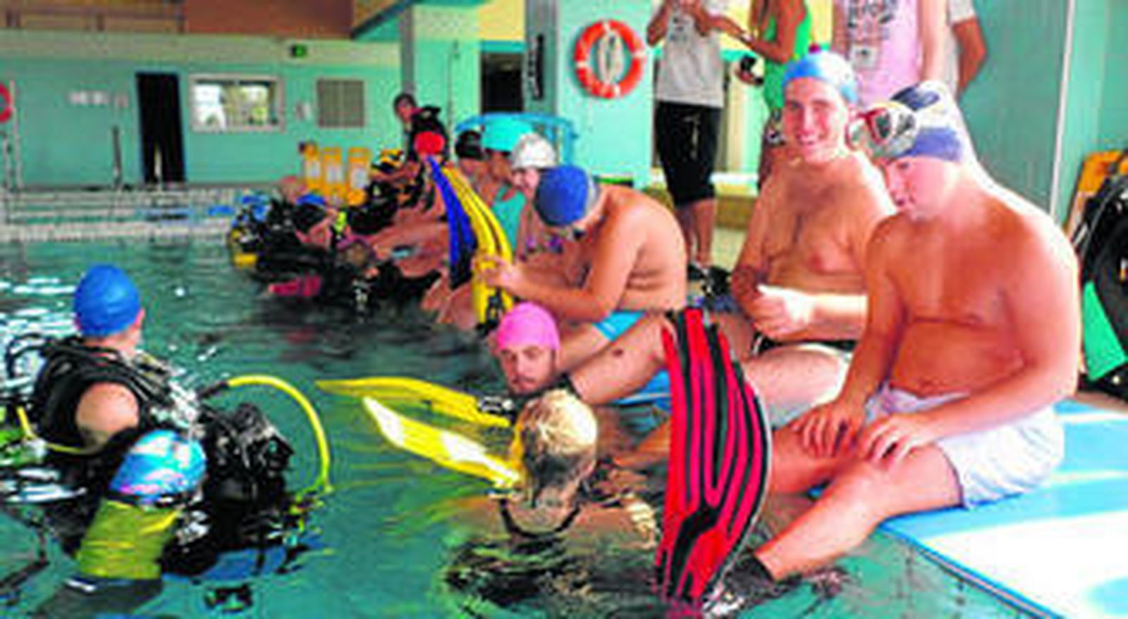 Participantes esperan en el bordillo de la piscina a su primera inmersión.