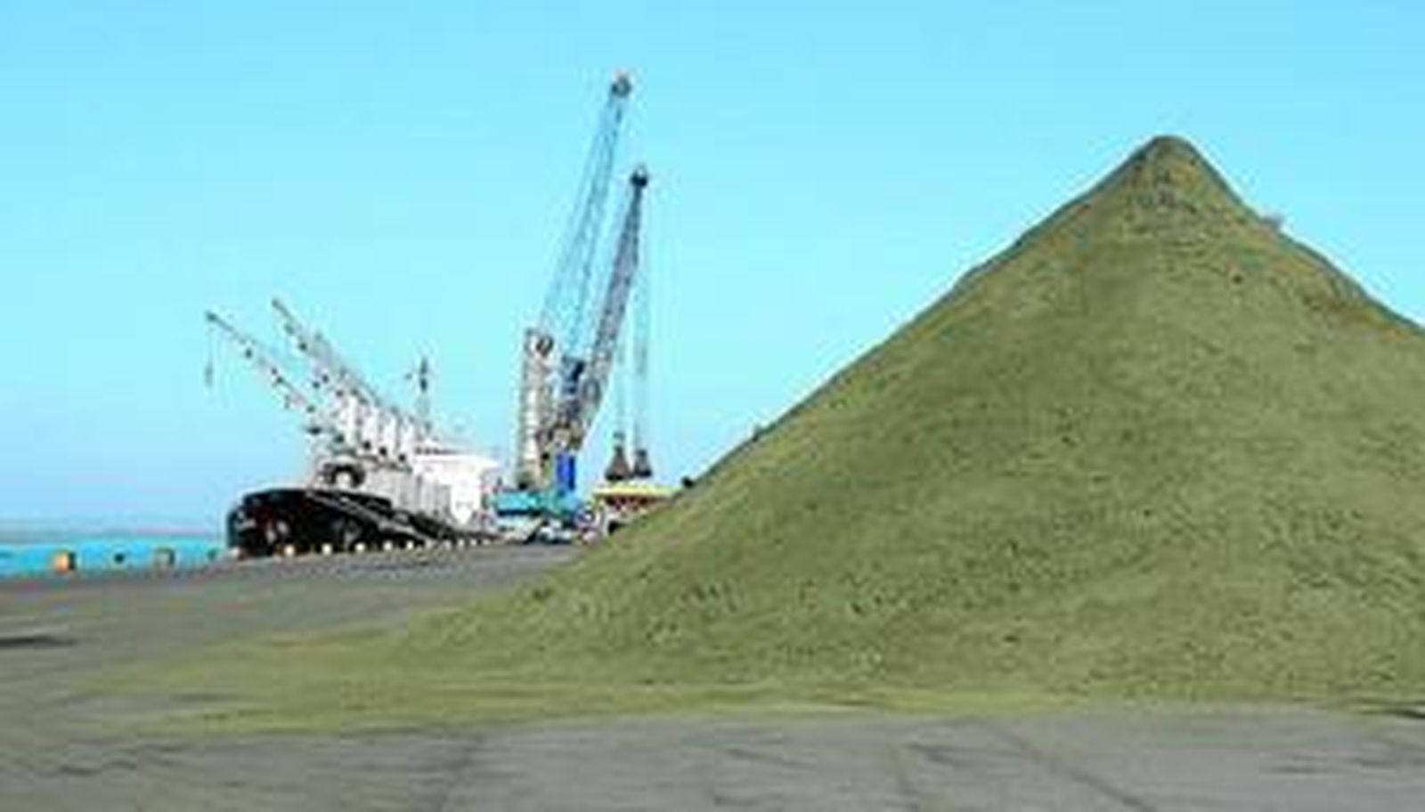 Una montaña de concentrado de cobre tras la que se está llevando a cabo la descarga de un barco, en el Muelle Juan Gonzalo.