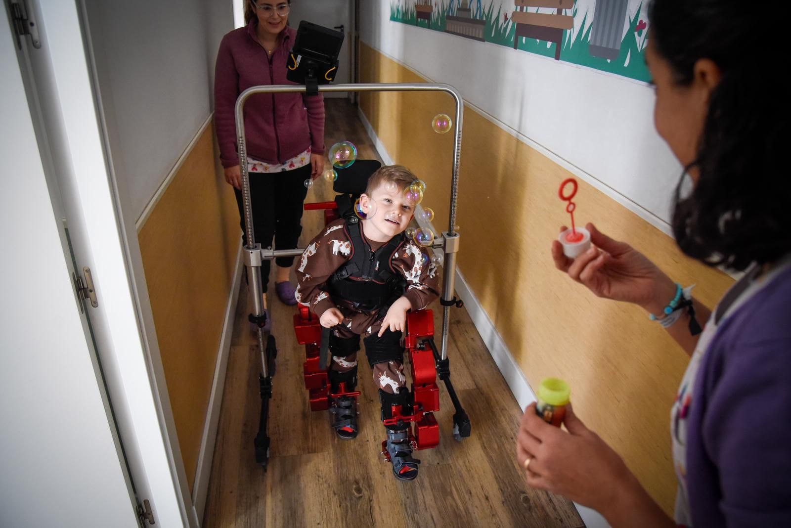Las fisioterapeutas del Centro de Estimulación Precoz del Buen Fin, Irene y Nieves, junto al pequeño Pepe, en plena terapia con el exoesqueleto.