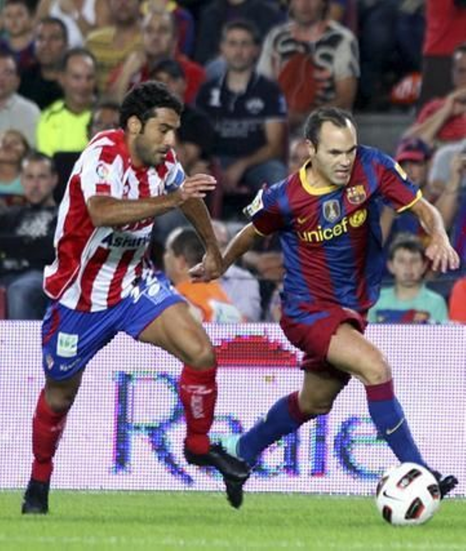 Iniesta corre perseguido por un rival. / EFE