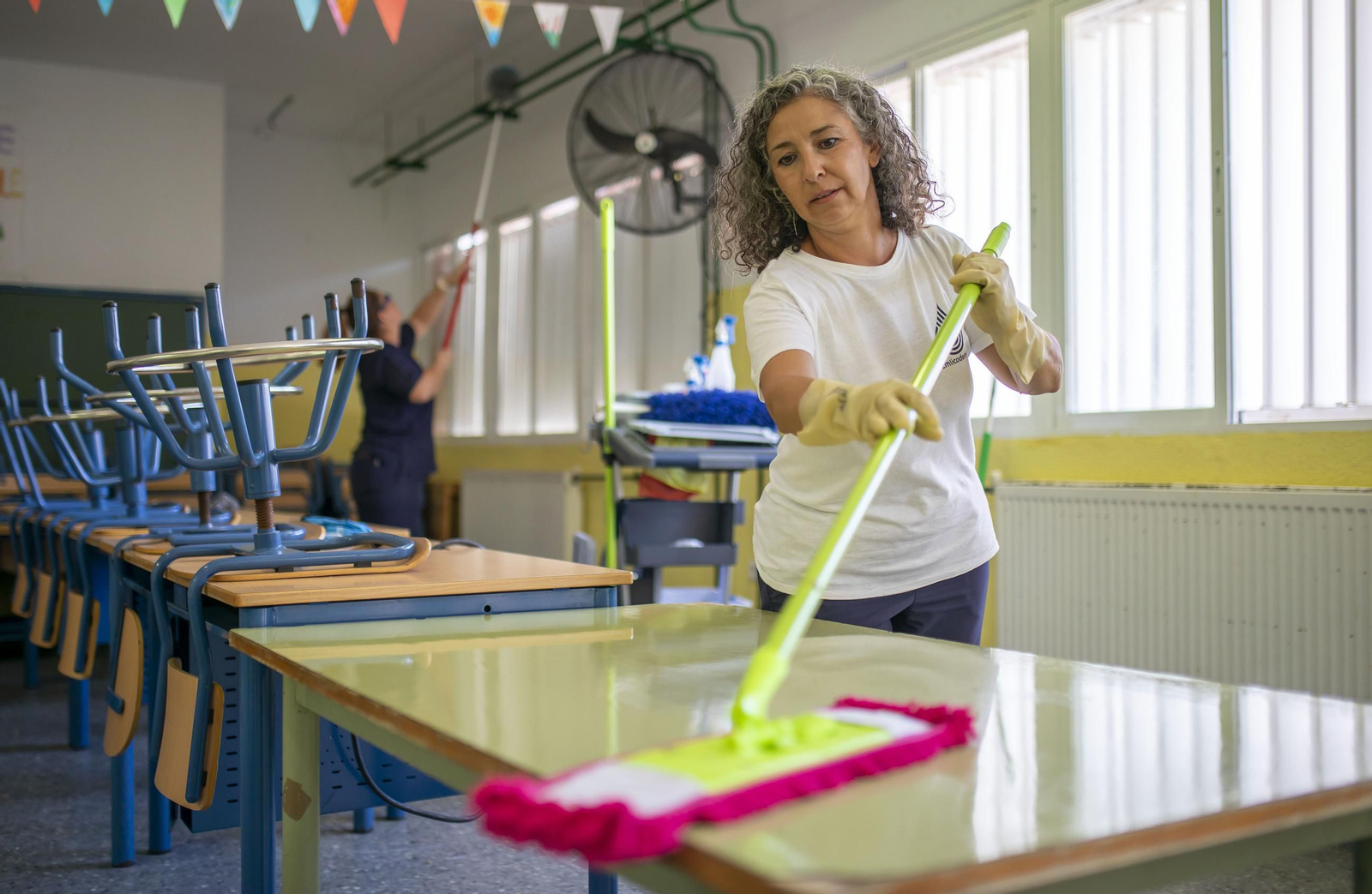 Una mujer limpia las mesas del aula de un colegio de Huelva.