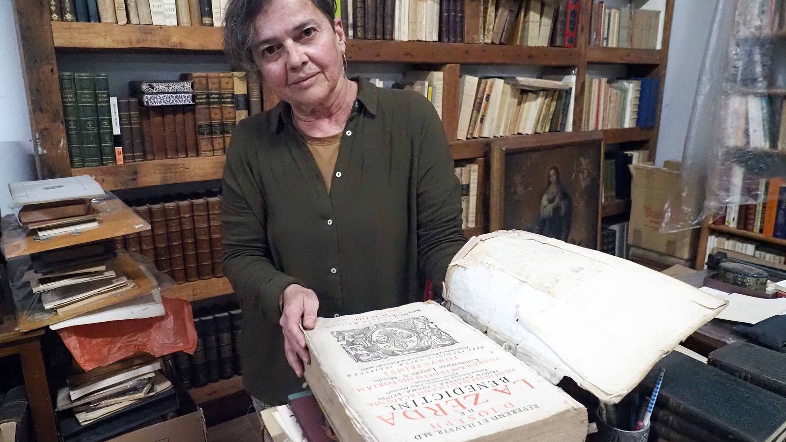 La anticuaria hojea uno de sus libros antiguos